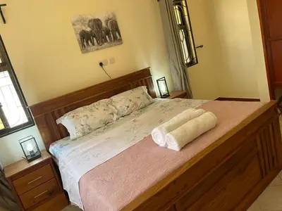 a bedroom with a large bed with a wooden frame at Emmalanta Safaris House in Arusha