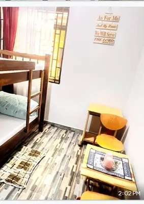 a room with a bed and a chair and a table at Divine Homestay Arusha in Arusha