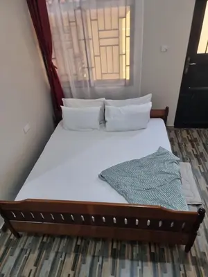 a bed with white sheets and pillows in a room at Divine Homestay Arusha in Arusha