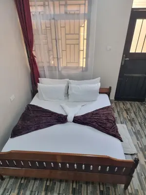 a bed with white sheets and pillows in a room at Divine Homestay Arusha in Arusha