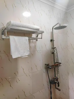 a shower in a bathroom with a white wall at River House Lodge in Arusha
