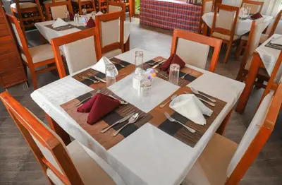 a table in a restaurant with a white table cloth and sidx sidx sidx at River House Lodge in Arusha