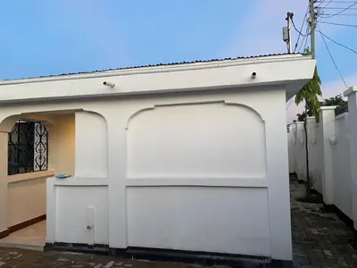 a white garage door on a white building at Jackpot BnB in Arusha