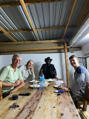 a group of people sitting around a wooden table at Jackpot BnB in Arusha