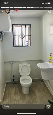 a bathroom with a toilet and a sink and a window at Jackpot BnB in Arusha
