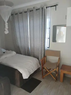 a bedroom with a bed and a chair and a window at Jackpot BnB in Arusha