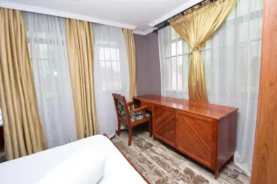 a bedroom with a desk and a bed and windows at Acres Hotels in Arusha