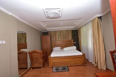 a bedroom with a bed and a chair in it at Acres Hotels in Arusha