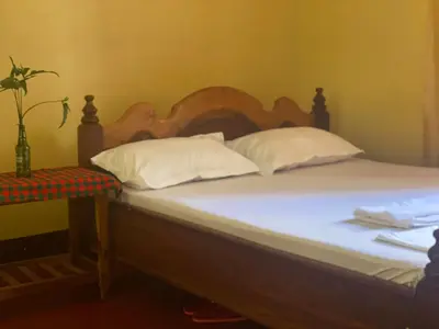 a bed with a wooden headboard and white pillows at Tourist Home in Moshi