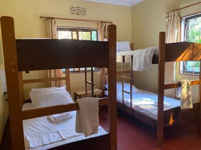 a room with three bunk beds and two windows at Tourist Home in Moshi