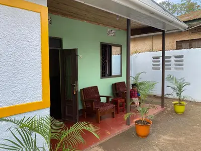 a porch of a house with two chairs and a table at Tourist Home in Moshi