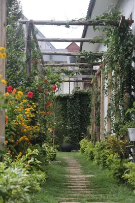 a garden with a pathway through a greenhouse with flowers at At Home Suites, Moshono Garden Arusha in Nkoanrua