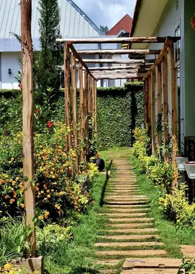 a garden path with a wooden pergola and flowers at At Home Suites, Moshono Garden Arusha in Nkoanrua