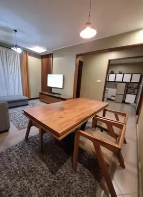 a living room with a wooden table and a chair at At Home Suites, Moshono Garden Arusha in Nkoanrua