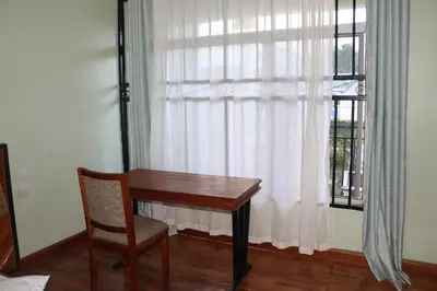 a desk and a chair in front of a window at At Home Suites, Moshono Garden Arusha in Nkoanrua