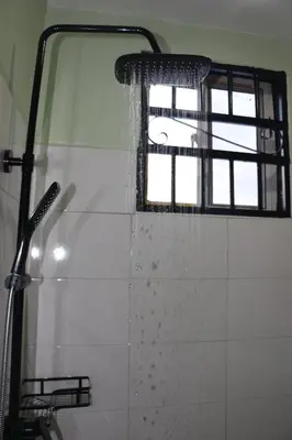 a shower in a bathroom with a window at At Home Suites, Moshono Garden Arusha in Nkoanrua
