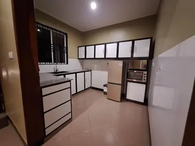 a large kitchen with white cabinets and appliances at At Home Suites, Moshono Garden Arusha in Nkoanrua