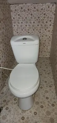a white toilet in a bathroom with a tile wall at Lambatini Homestays & Lodges in Arusha