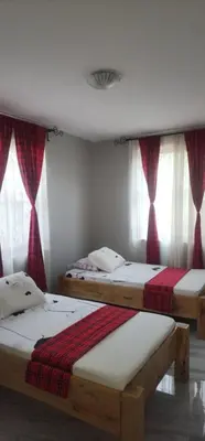 two beds in a room with windows at Lambatini Homestays & Lodges in Arusha