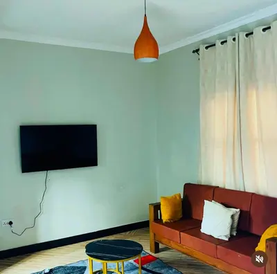 a living room with a couch and a tv on a wall at Kanyigo homes Apartments in Arusha