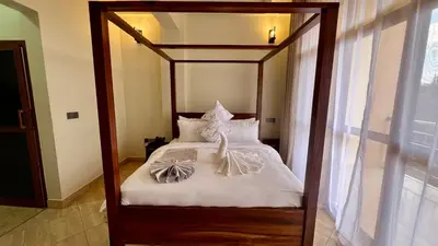 a bedroom with a canopy bed with white sheets at Skylark Hotel in Karatu