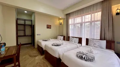 a hotel room with three beds and a window at Skylark Hotel in Karatu