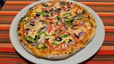 a pizza on a white plate on a table at Arusha Centre Rooms in Arusha