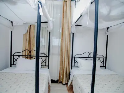two beds with black posts in a bedroom at Arusha Centre Rooms in Arusha