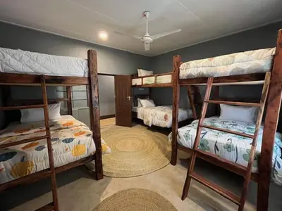 a room with three bunk beds and a fan at Moshi Urban Hostel and Backpackers in Moshi