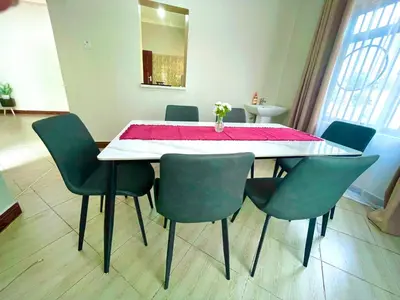 a dining room table with green chairs and a pink table cloth at Ngorongoro Gateway Homestay in Karatu