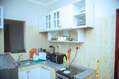 a kitchen with white cabinets and a sink at Ngorongoro Gateway Homestay in Karatu