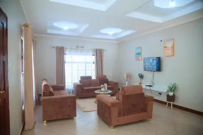 a living room with couches and chairs and a tv at Ngorongoro Gateway Homestay in Karatu