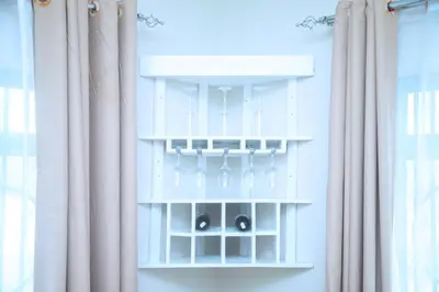 a white shelf with glasses on it next to curtains at Ngorongoro Gateway Homestay in Karatu