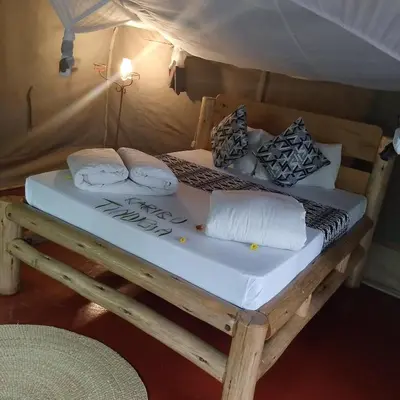 a bed in a tent with pillows on it at Tindiga Tented Camp Eyasi in Mangola