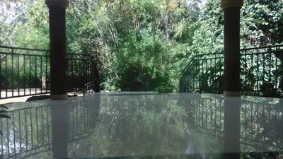 a glass table on a balcony with trees in the background at Njiro Ebenezer Retreat Lodge in Arusha