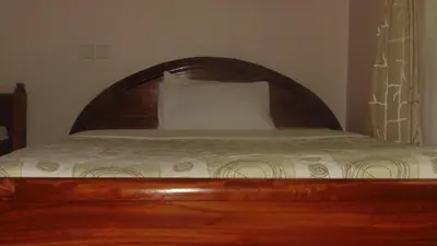 a bed with a wooden headboard and a pillow at Njiro Ebenezer Retreat Lodge in Arusha