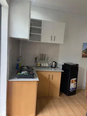 a kitchen with white cabinets and a black refrigerator at Kishongo house in Arusha