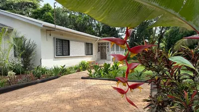 a plant with red flowers in front of a house at Malaika Oasis in Moshi