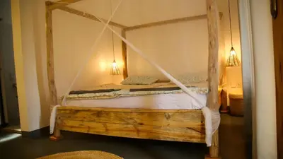 a bedroom with a wooden bed with a canopy at Hakuna in Arusha