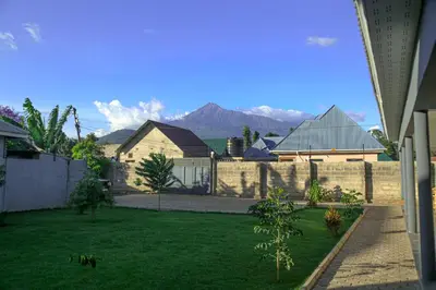 a yard with a fence and a house and mountains at Hakuna in Arusha