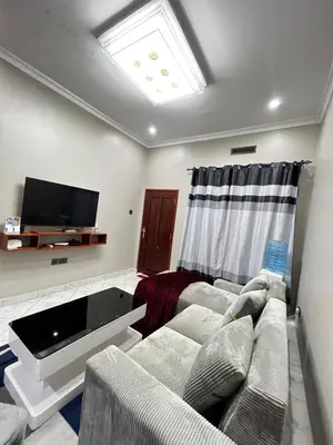 a living room with a couch and a flat screen tv at Hadraj Clocktower Apartment1 in Arusha
