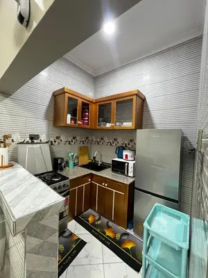 a kitchen with wooden cabinets and a stainless steel refrigerator at Hadraj Clocktower Apartment1 in Arusha