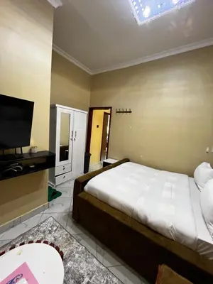 a bedroom with a large bed and a flat screen tv at Hadraj Clocktower Studio Apt in Arusha