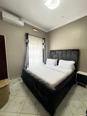 a bedroom with a large bed with a black leather headboard at Hadraj Clocktower Apartment2 in Arusha