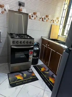 a kitchen with a stove and a kitchen with a book on the floor at Hadraj Clocktower Apartment2 in Arusha