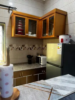 a kitchen with wooden cabinets and a refrigerator at Hadraj Clocktower Apartment2 in Arusha