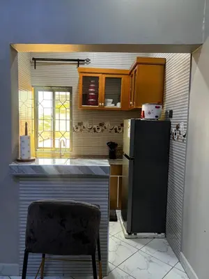 a kitchen with a black refrigerator and a chair at Hadraj Clocktower Apartment2 in Arusha