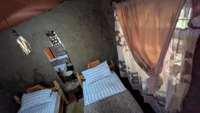 a room with two beds and a window at Alkebulan Farm House in Moshi