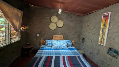 a bedroom with a bed in a stone wall at Alkebulan Farm House in Moshi