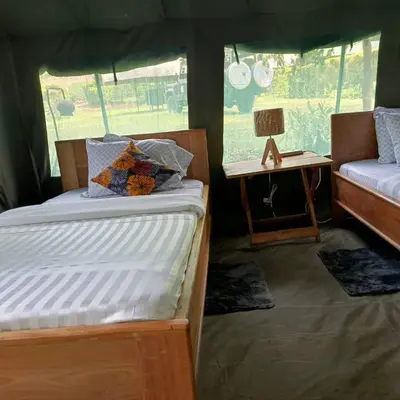a bedroom with two beds and a table with a lamp at MCF LUXURY Tents in Moshi